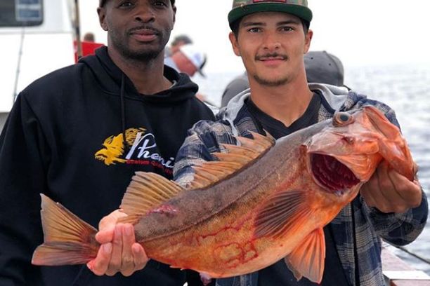 2 men holding an orange fish